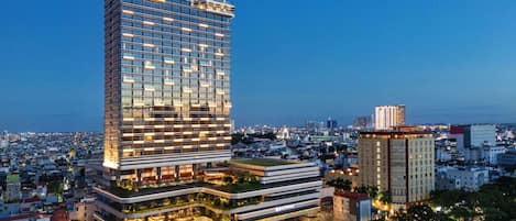 A high-rise hotel with multiple floors, a prominent name at the top, and a surrounding urban area with other buildings.