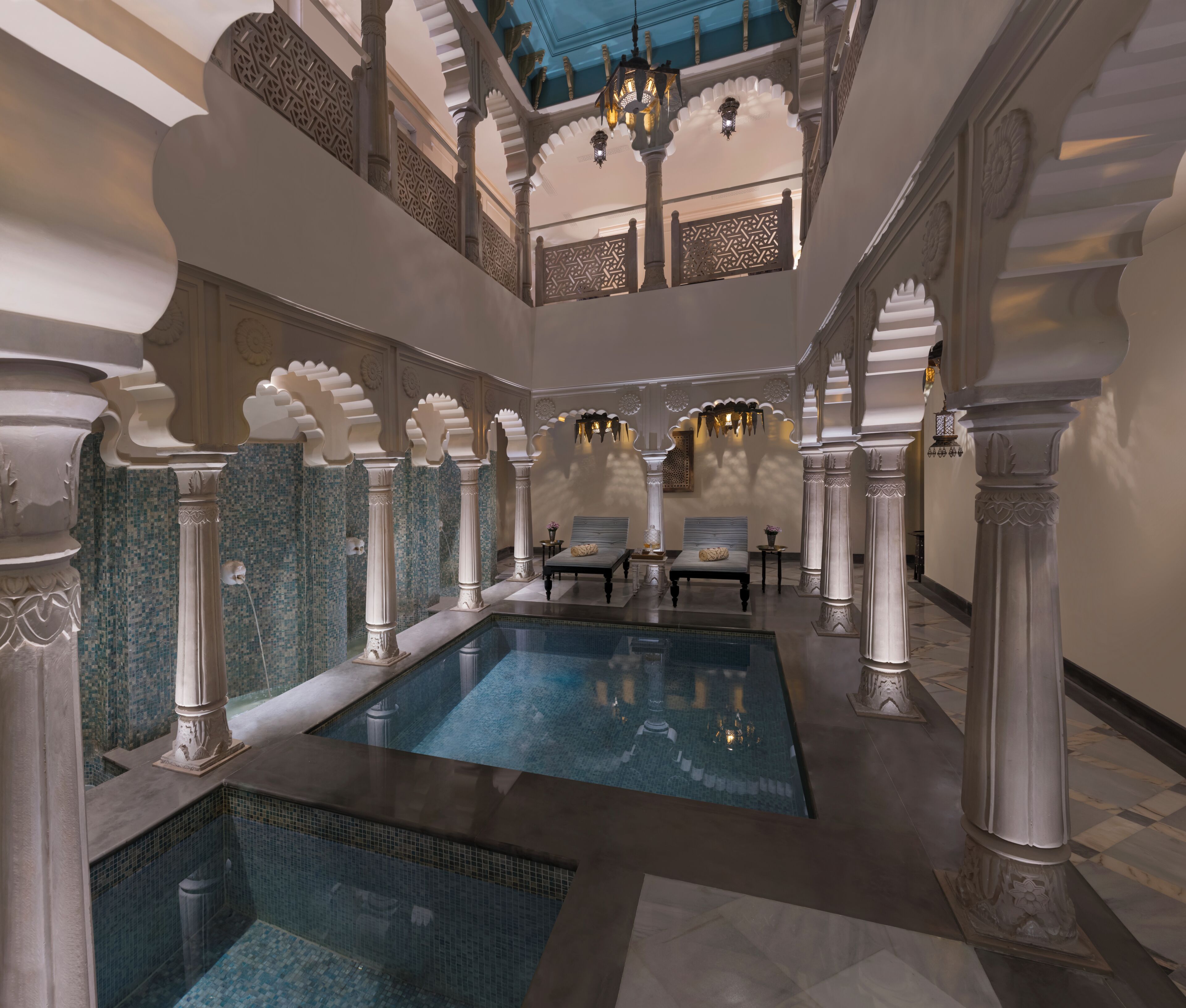 Una piscina interior con columnas ornamentales y un techo de detalles intrincados.