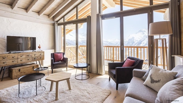 A spacious living room with a large TV, wooden furniture, and a view of snow-capped mountains through large windows. - Wifi, sauna, terrace, balcony, parking, tv, ski locker, 80-95m², La Rosière (La Rosière Montvalezan)