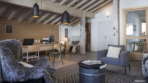 A modern living room with a wooden ceiling, a desk with a computer, a grey armchair, and a fur-covered chair. - Wifi, sauna, balcony, parking, tv, ski locker, 125m², La Rosière (La Rosière Montvalezan)