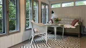 Une pièce comprenant un fauteuil en osier, une table ronde, un canapé et un tapis à motifs.