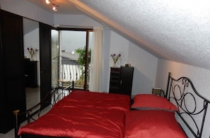 A bedroom with a bed, a dresser, and a window with a view of the outside.