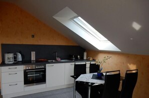 Une cuisine moderne dotée d’une verrière, de meubles blancs et d’un coin repas avec des chaises noires.