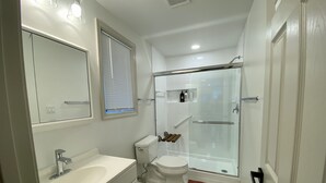 A bathroom with a white sink, toilet, and glass-enclosed shower.