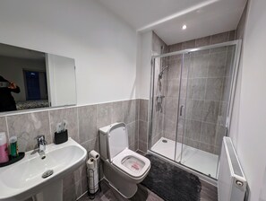 Une salle de bain moderne avec un lavabo, des toilettes et une douche à parois de verre.