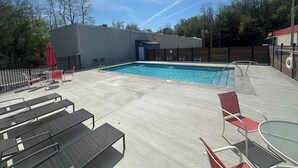 A swimming pool with lounge chairs and a covered seating area. - Lighthouse Inn & Suites (Hannibal)
