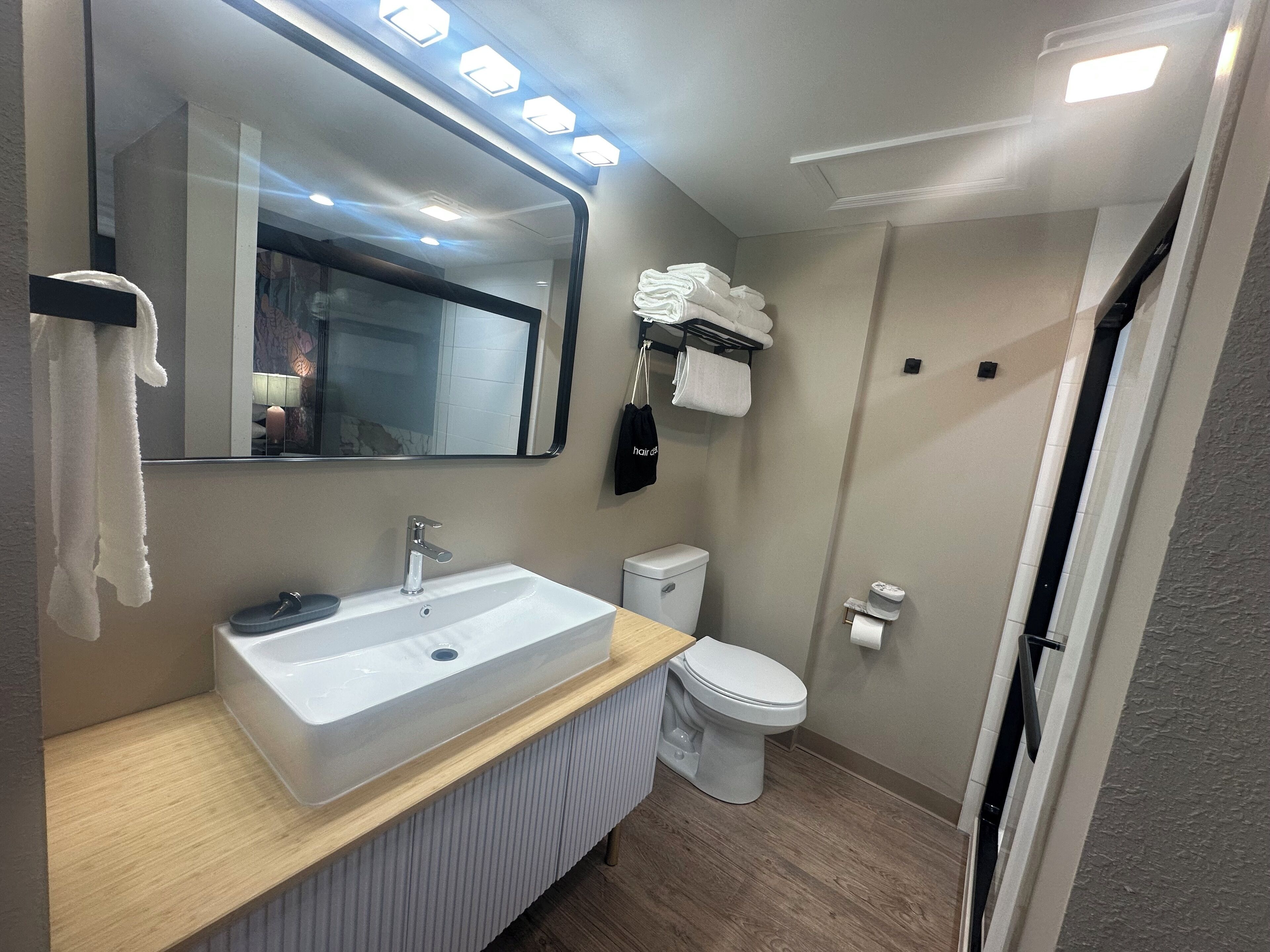 Une salle de bain moderne avec un grand miroir, un lavabo blanc et des toilettes.