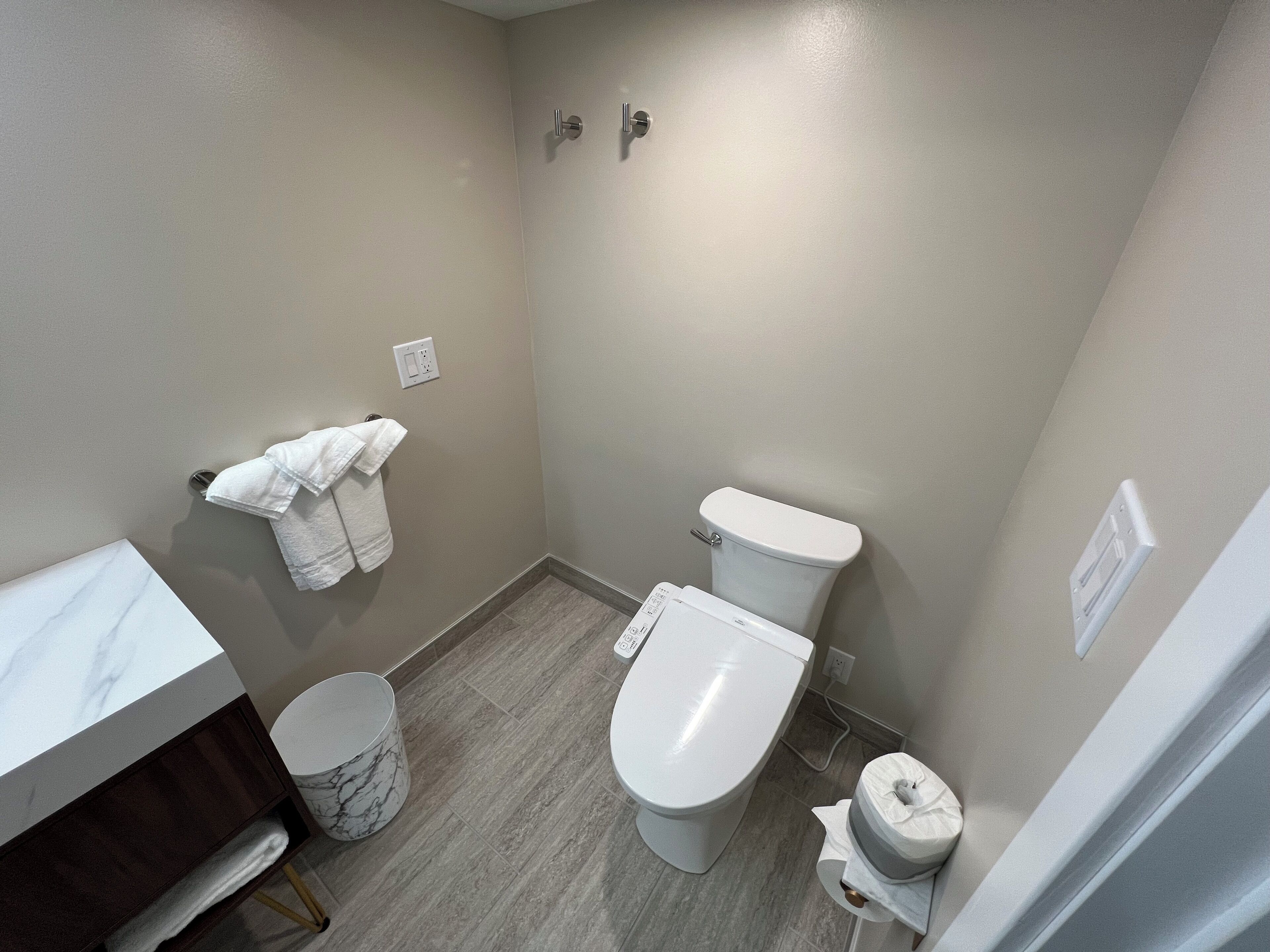 A small bathroom with a toilet, a sink, and a marble-topped vanity.