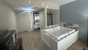 A spacious bathroom with a large bathtub, a walk-in shower, and a vanity with a mirror. - Lighthouse Inn & Suites (Hannibal)