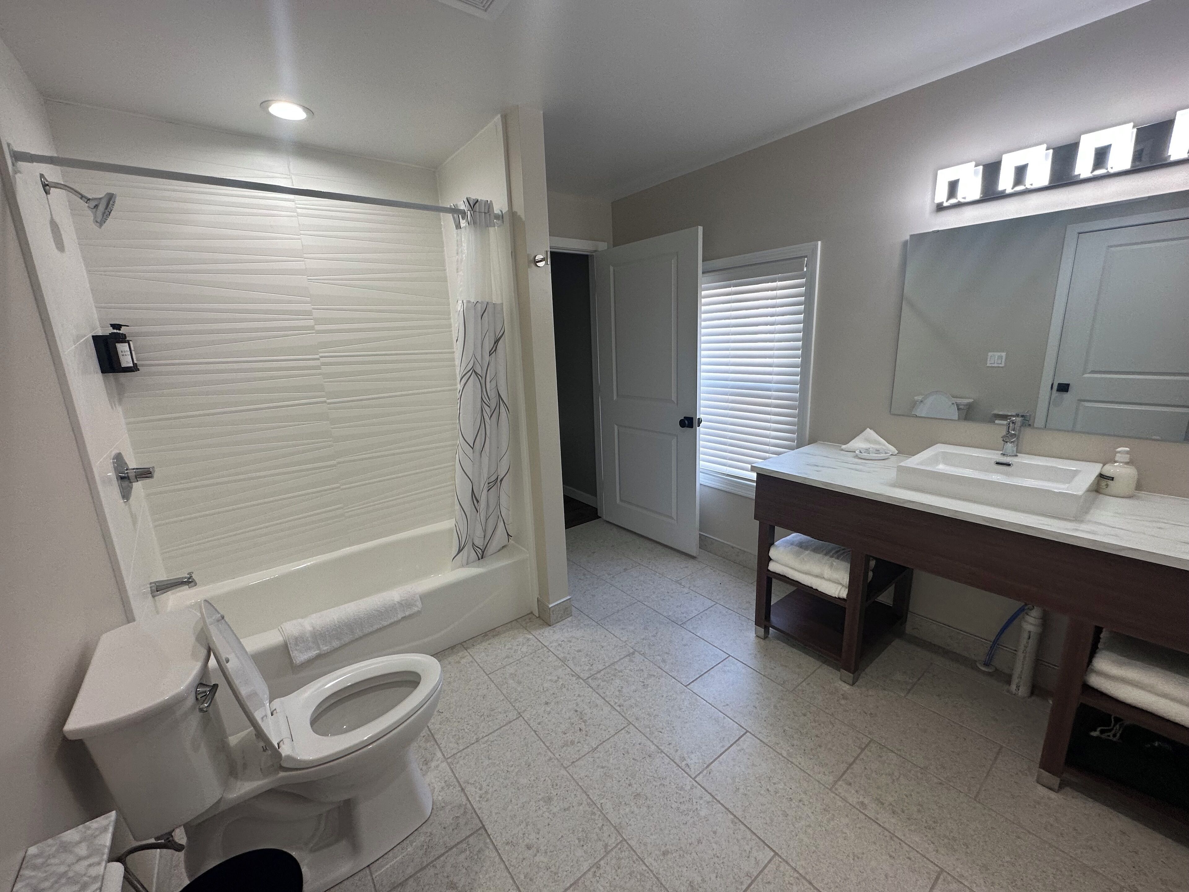 A bathroom with a toilet, shower, and sink.