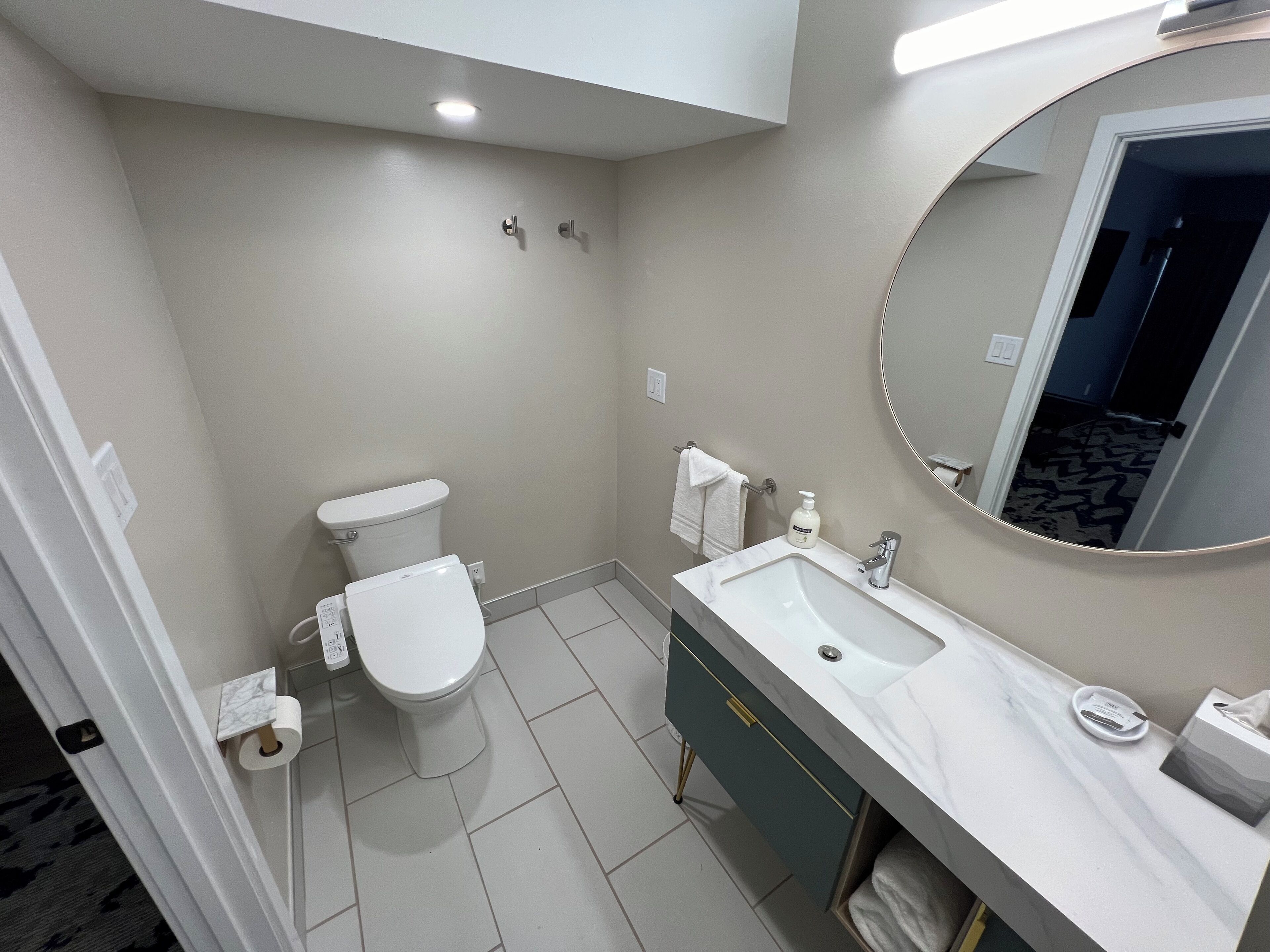 A modern bathroom with a toilet, sink, and mirror.