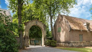 Una entrada con arco de piedra que conduce a un edificio con techo de tejas y una placa.