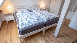 Et soveværelse med en seng, to sengeborde, et natbord, en lysekrone og et klædeskab.