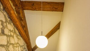 En trætrap med synlige bjælker, en hængende lampe og en væg med ru overflade.