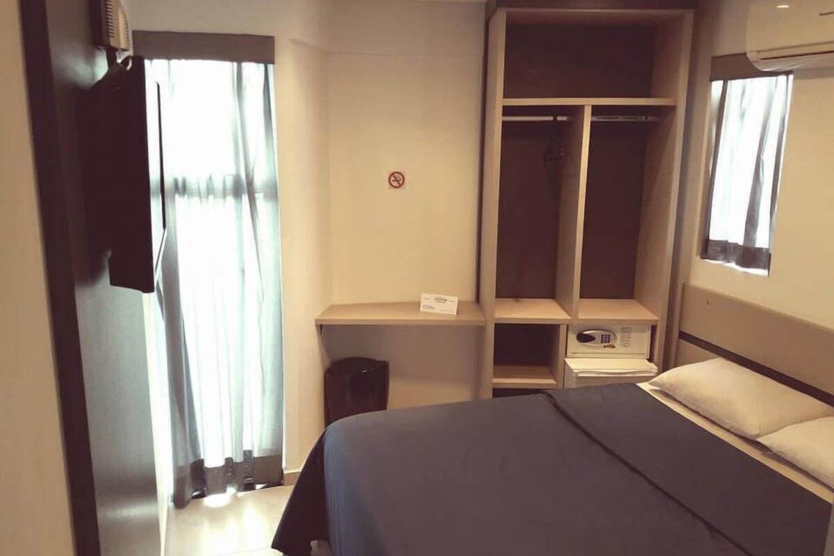 Une chambre d’hôtel avec un lit, une armoire, un bureau et une fenêtre.