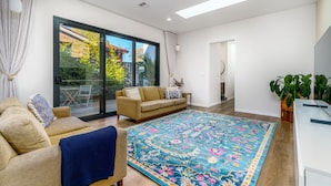 Una sala de estar moderna con un sofá, un tapete estampado y un ventanal corredizo que da a un espacio exterior.