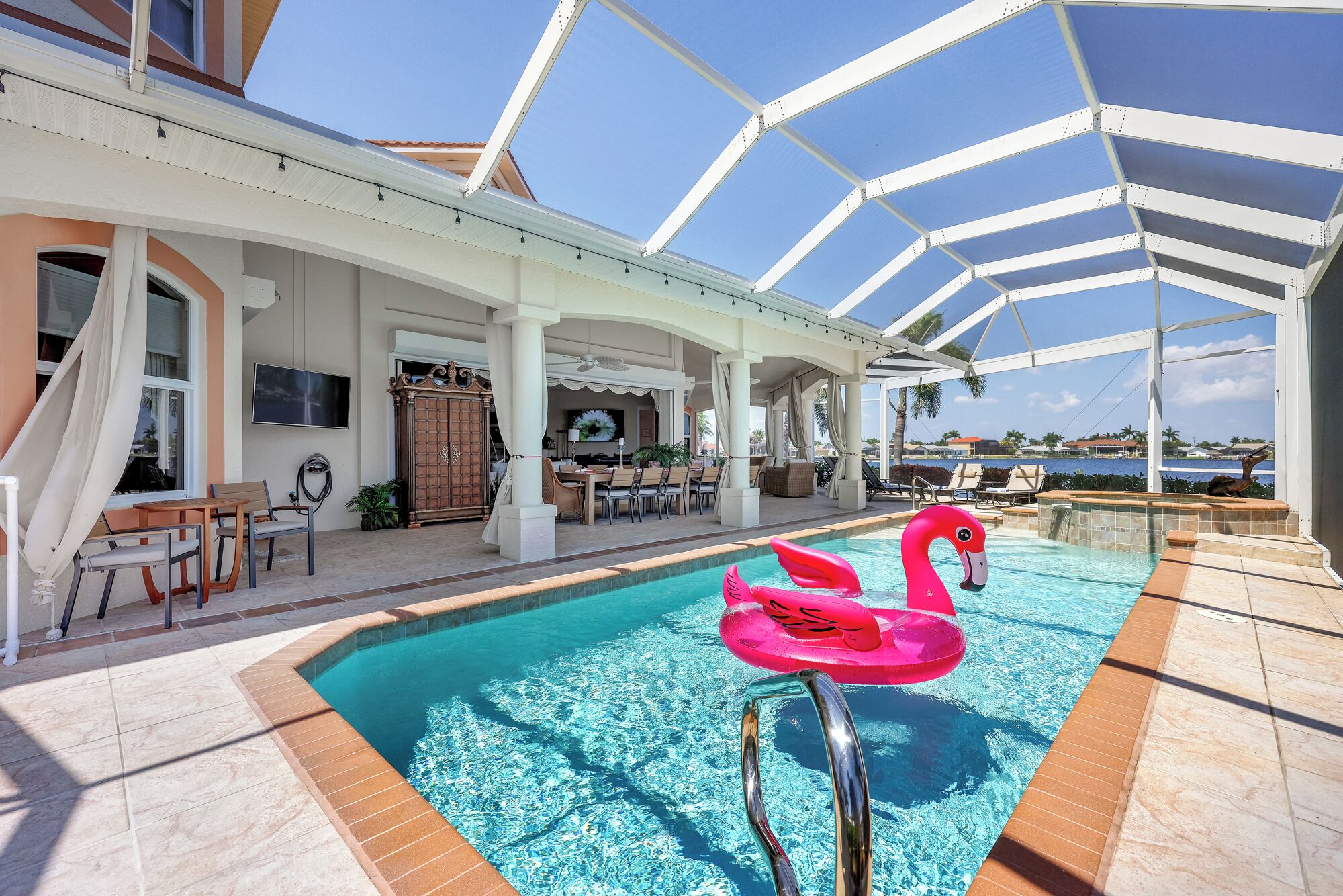 Un espace piscine agrémenté d’un flotteur en forme de flamant rose, d’un coin salon abrité et d’une vue sur la mer.