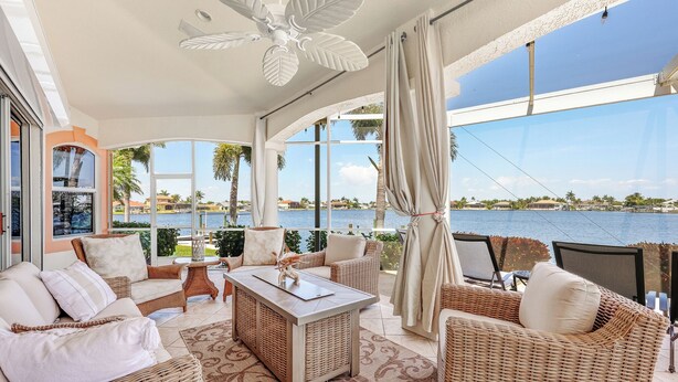 A spacious balcony with wicker furniture, a ceiling fan, and a view of a lake. - Your Private Paradise Awaits – Experience Luxury at villa paradise (Cape Coral)