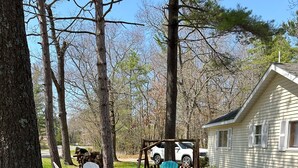Une maison dotée d’un porche, entourée d’arbres et offrant un espace de détente extérieur.