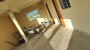 Una habitación con suelo de baldosas, un cuadro en la pared y una zona de estar con sillas y una mesa.