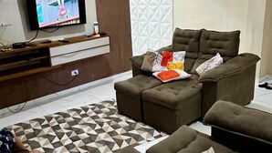 Una sala de estar con un conjunto de sofá, un televisor y un piso con diseño.