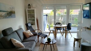 A living room with a sofa, a coffee table, and a dining area with chairs and a table. - Charming Apartment in Norden (Norden)