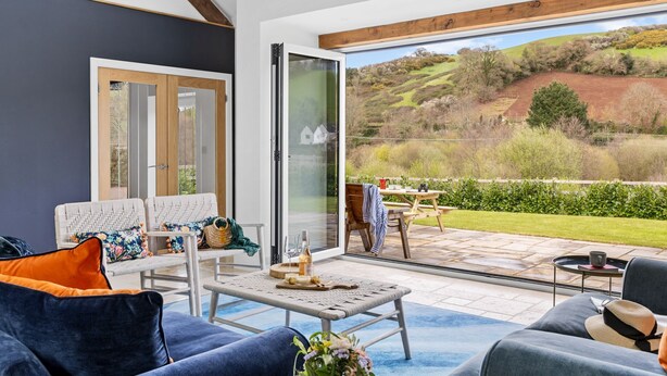 A modern living room with a large sliding glass door leading to an outdoor patio. - The Shippon -  Free Parking, Free WiFi, EV Charger, Coffee Machine, Large Garden (Dawlish)
