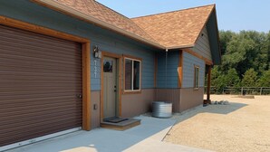 A two-story building with a garage door, a front door, and a small porch area. - The Guest House at Rod and Rifle Ranch (Corvallis)