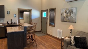 A spacious kitchen with a granite countertop, wooden chairs, and a dining area. - The Guest House at Rod and Rifle Ranch (Corvallis)