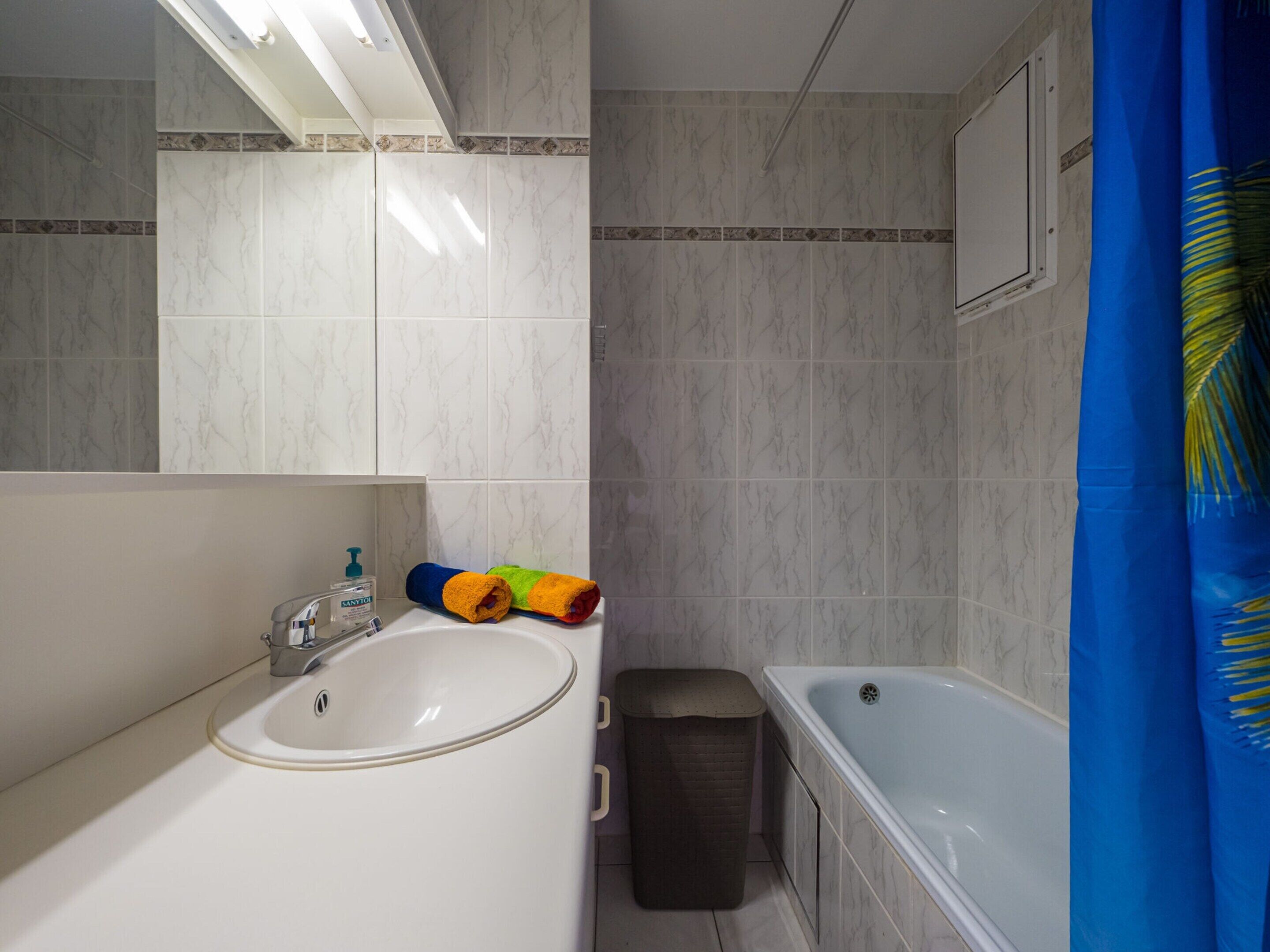 A bathroom with a white sink, a bathtub, and a shower curtain.