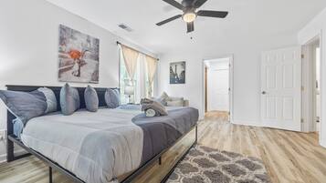 Une chambre à coucher avec un lit, un ventilateur de plafond et des œuvres d’art accrochées aux murs.
