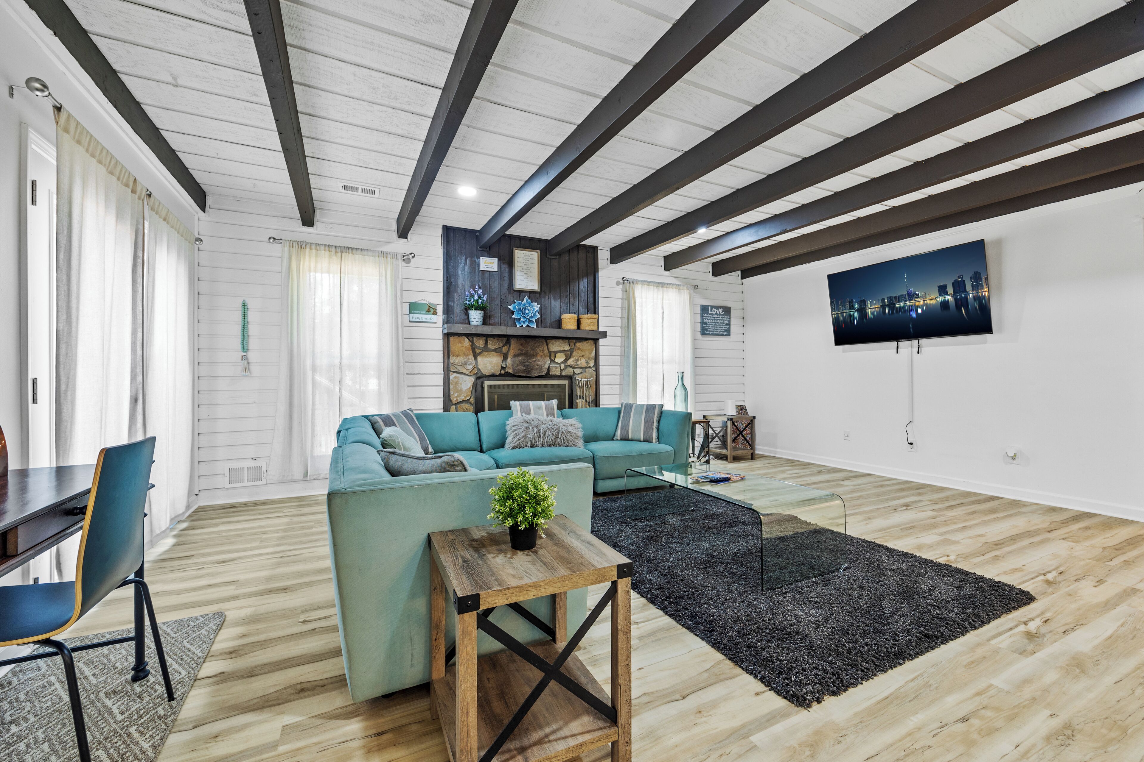 Un salon moderne avec un canapé de couleur turquoise, une table basse en bois et un tapis noir.
