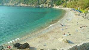 A beach with clear turquoise waters, rocky outcrops, and a few people. - Holiday Villa Martini With Pool, in Ermones Beach, Vatos, Corfu (Corfu)