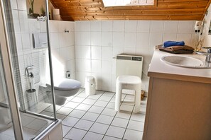A bathroom with a glass shower enclosure, a toilet, a sink, and a white trash bin. - Find Your Holiday Home in the Harz Mountains (Oberharz am Brocken)