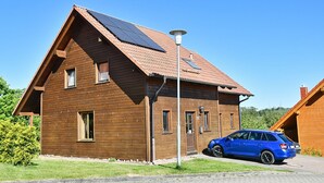 A wooden house with solar panels, a car parked in front, and a street lamp. - Find Your Holiday Home in the Harz Mountains (Oberharz am Brocken)