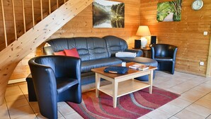 A cozy living room with a wooden ceiling, a sofa, two armchairs, a coffee table, and a rug. - Find Your Holiday Home in the Harz Mountains (Oberharz am Brocken)