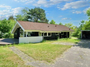 A single-story house with a tiled roof, a covered porch, and a small shed.