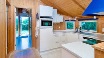 Una cocina moderna con paredes de madera, horno empotrado y ventana con vistas a la vegetación.
