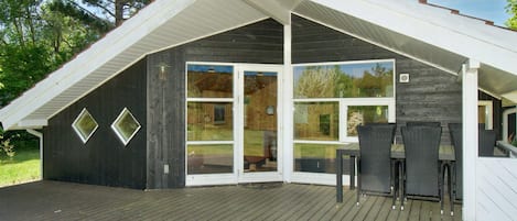 A covered outdoor deck with a dining area and a large sliding glass door leading to a backyard.