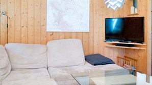 Un saló modern amb un sofà modular, una televisió de pantalla plana i una taula de centre de vidre.