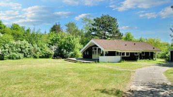 A single-story building with a sloped roof, a porch, and a paved driveway.