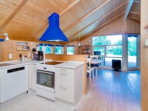 Une cuisine moderne avec des meubles blancs, un four encastré et une hotte de couleur bleue.