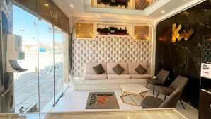 A modern hotel lobby with a checkered wall, a sofa, armchairs, and a reception desk. - KW HOTEL (Uyuni)
