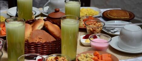Una mesa con diversos alimentos para el desayuno, como pan, frutas y bebidas.