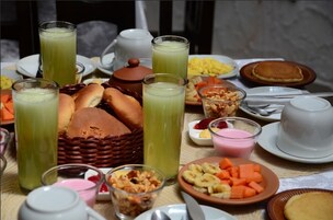Una mesa con diversos alimentos para el desayuno, como pan, frutas y bebidas.