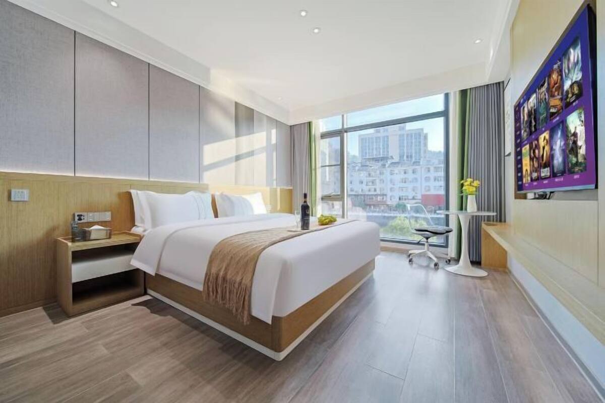 Une chambre d’hôtel moderne avec un grand lit, un bureau et une vue sur la ville.