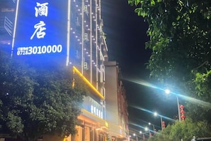 Un edificio con letreros iluminados, un número visible y acceso directo desde la calle.
