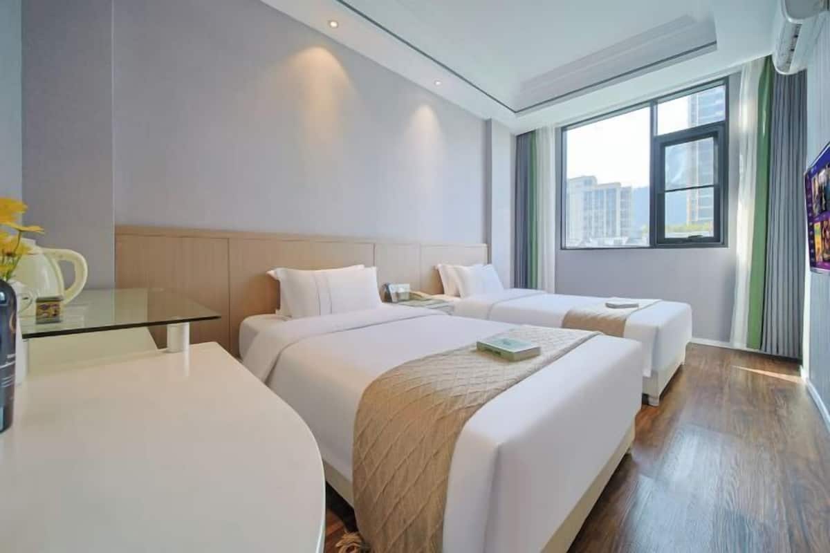 Une chambre d’hôtel avec deux lits, une table en verre, une machine à café et une vue sur les immeubles par la fenêtre.
