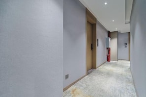 Ein Flur mit Teppichboden, einer Holztür und einem Lichtschalter an der Wand.