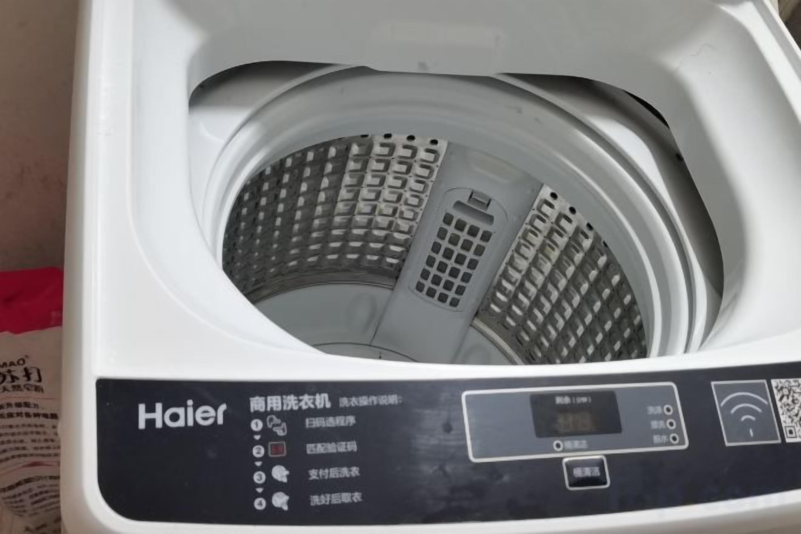 A white Haier washing machine with a control panel and a QR code.